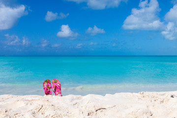 Fototapeta na wymiar Pair of colored sandals on a white sand beach