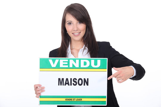 French Estate Agent with a 'Vendu' sign