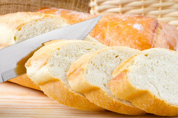 Freshly baked baguette sliced on wooden cutting board