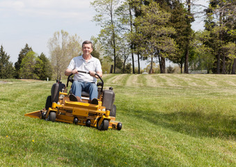 Senior man on zero turn lawn mower on turf © steheap
