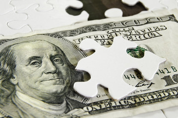 Closeup of a US $100 bill and puzzle piece