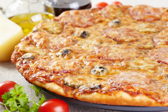 Italian cuisine. Pizza with salami, pickles and olives