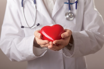 Female doctor with stethoscope holding heart