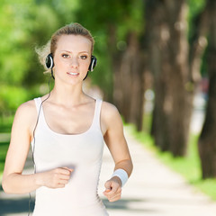 Fototapeta premium Young woman running in green park