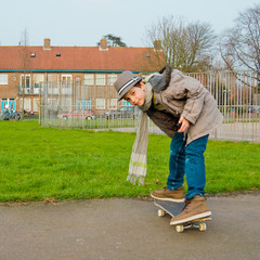 Cute teenage boy with mobile phone on the skateboard