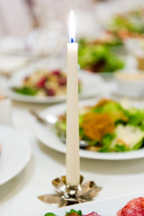 Burning candle at dinner table