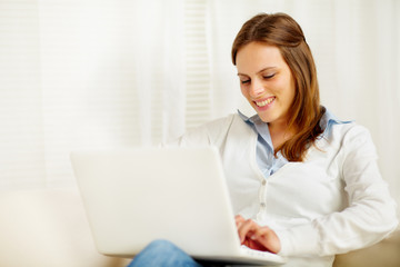 Cute young woman smiling and working on laptop