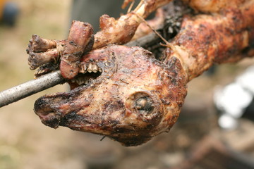 Roasting head of a lamb on a spit outdoors