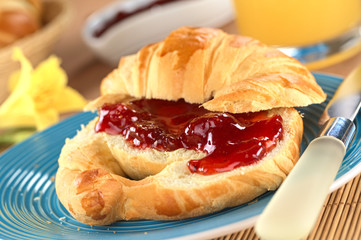 Croissant with butter and strawberry jam