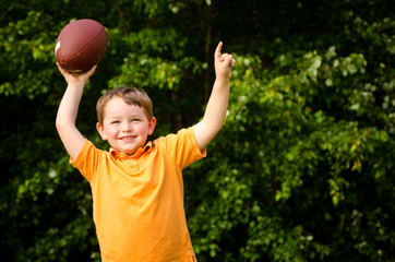 Child with football celebrating by showing that he's Number 1
