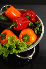 Freshly vegetables in metal colander isolated over black