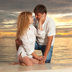 Young couple on the sea sunset background