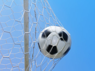 Football spinning in goal against blue sky