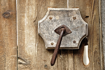 A very old door handle on a wooden door