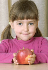 Pequeña niña comiendo una manzana roja.