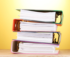 bright office folders on wooden table on yellow background.