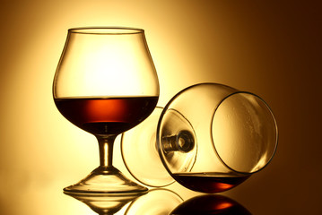 Two glasses of cognac on yellow background