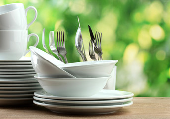 Clean dishes on wooden table on green background
