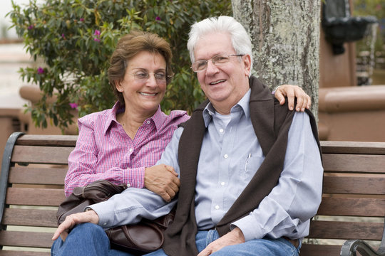 Happy Senior Couple Sitting On Park Bench