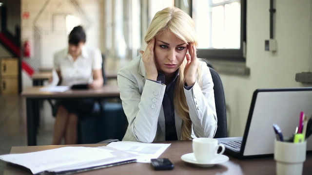 Young attractive businesswoman having headache in the office