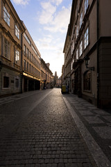Fototapeta na wymiar Dawns light reflects off windows and stones on Prague street