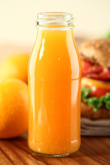 A bottle of Orange juice with Fruits and sandwich.