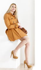 sitting woman wearing brown coat and pumps with a handbag