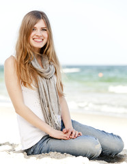 Fototapeta na wymiar Funny teen girl sitting near the sea.