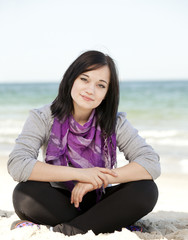 Fototapeta na wymiar Funny teen girl sitting on the sand at the beach.