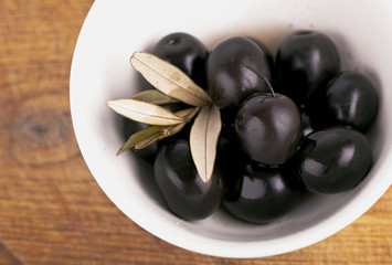 Olives on the wooden table on a white plate