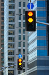 Two traffic lights against background of modern buildings.