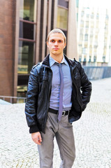 Portrait of successful young guy against urban background