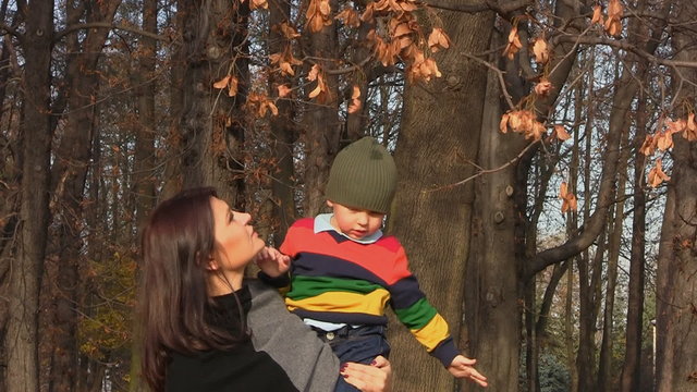 Mother holds son on her hands at autumn