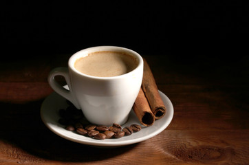 cup with coffee, cinnamon and coffee beans on  wooden table