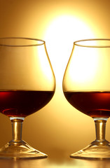 Two glasses of cognac on yellow background closeup