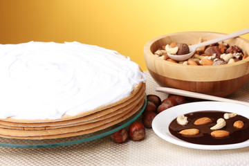 cake on glass stand and nuts on table on yellow background