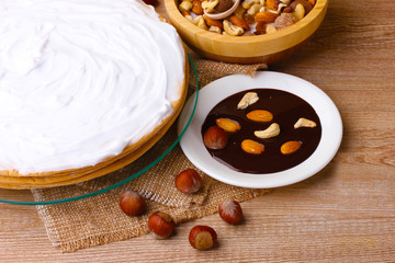 cake on glass stand and nuts on wooden  table