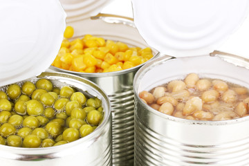 Open tin cans of corn, beans and peas isolated on white