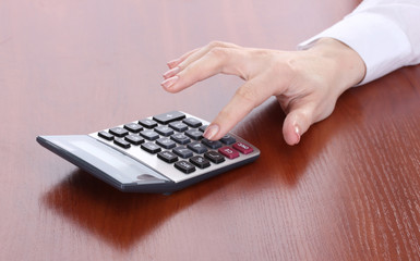 women hand and Calculator on wooden table