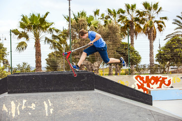 boy rides his scooter at the skate park