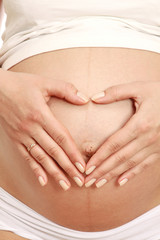 Closeup of a pregnant woman touching her belly with hands