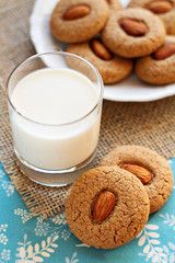 Two almond cookies with a glass of milk