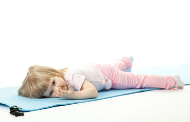 Baby girl relaxing after sport on a training mat