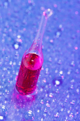 Red ampoule on abstract water drops background, macro view