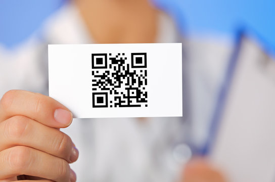 Doctor holding business card with health care QR code on blue