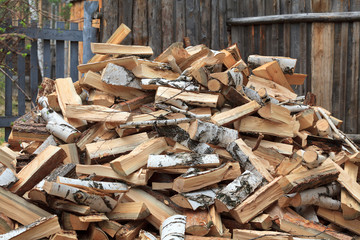 Pile of firewood against old wooden fence
