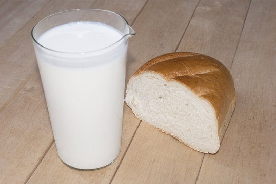 Glass fresh milk and bread over boards background