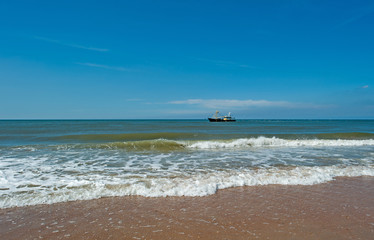 Trawler fishing at sea under a blue sky