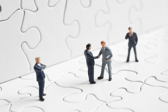 Business figures shaking hands on a puzzle