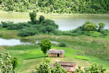 Beautiful landscape with huts, a boat, water and green land